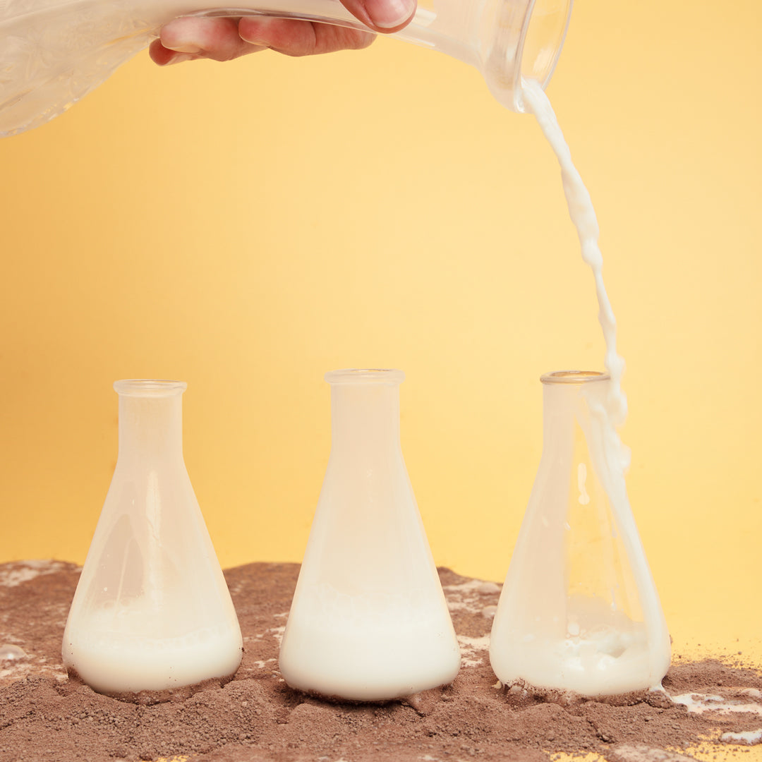 milk jar poring into chemical containers surrounded by chocolate powder